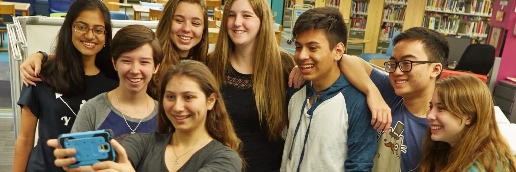 group of teens standing together taking a selfie.
