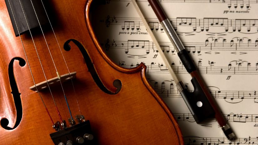Close up of a violin laid on top of sheet music